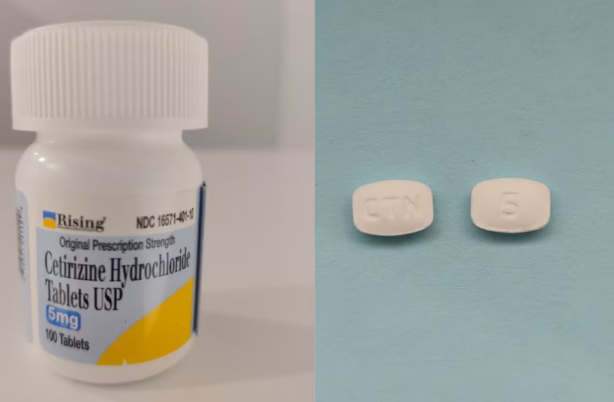 Close-up of a bottle labeled cetirizine hydrochloride 5 mg tablets beside two white allergy medication tablets, illustrating an allergy medication cross contamination recall.