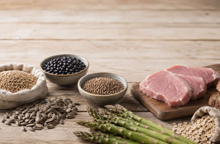 Whole foods rich in vitamin B1, including brown rice, sunflower seeds, lentils, pork, and whole grains, arranged on a wooden table